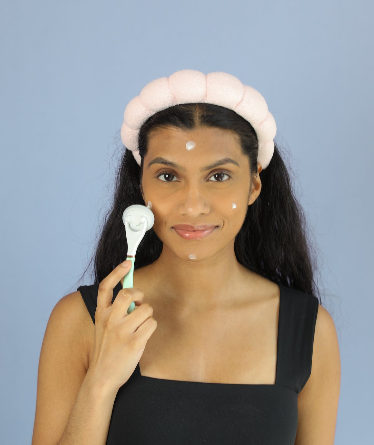 woman holding applicator tool to face before applying product